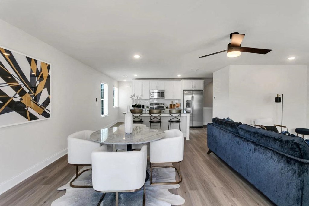 A modern dining room with a glass table and white chairs.