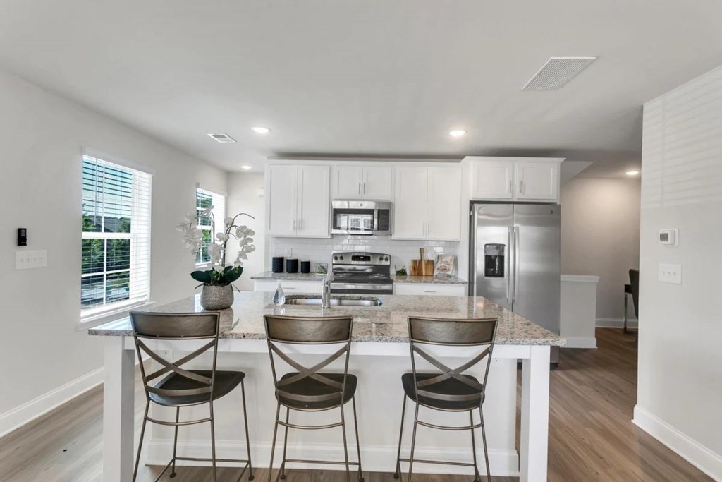 A modern kitchen with a center island and bar stools.