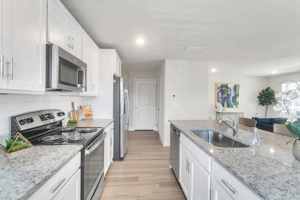 A kitchen with granite countertops and white cabinets.