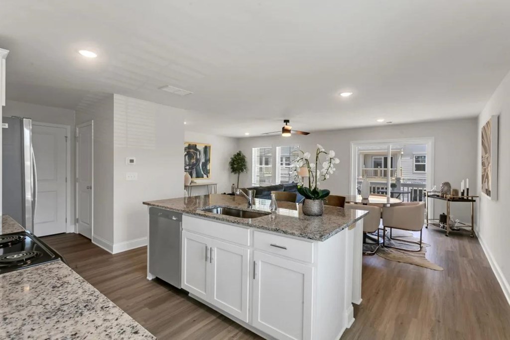 A modern kitchen with a marble countertop and wooden flooring.