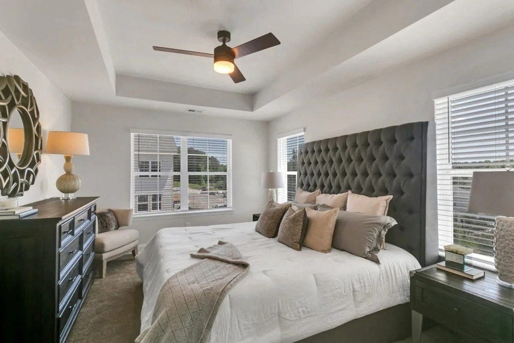 A bedroom with a large bed, a dresser, and a ceiling fan.
