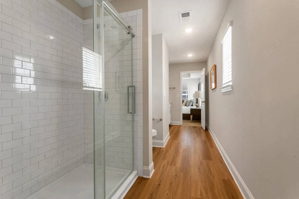 A long hallway with a glass shower door on the left.