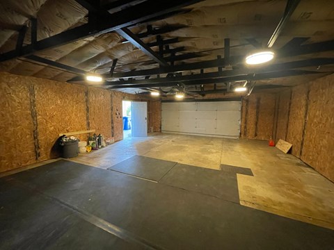 A large empty room with a black floor and walls covered in insulation.