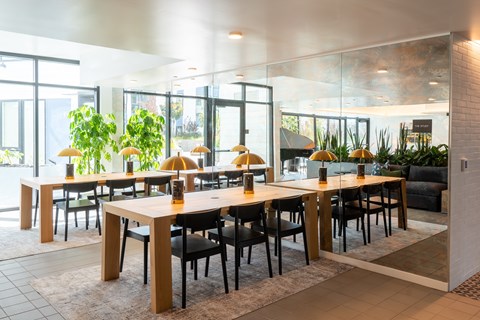 A dining room with tables and chairs and a glass wall.