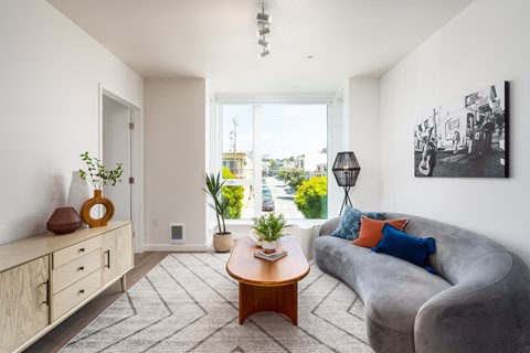 A living room with a grey couch, a wooden coffee table, and a painting on the wall.