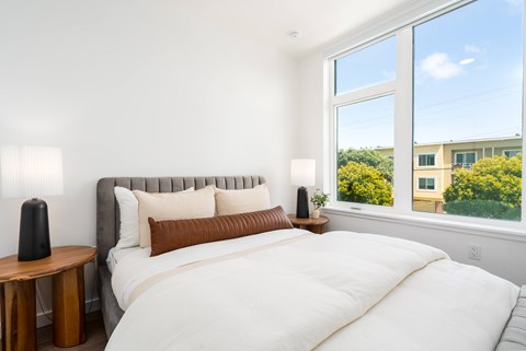 A bedroom with a large bed and a window overlooking a building.