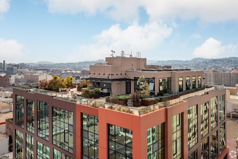 A modern building with a lot of windows and plants on the roof.