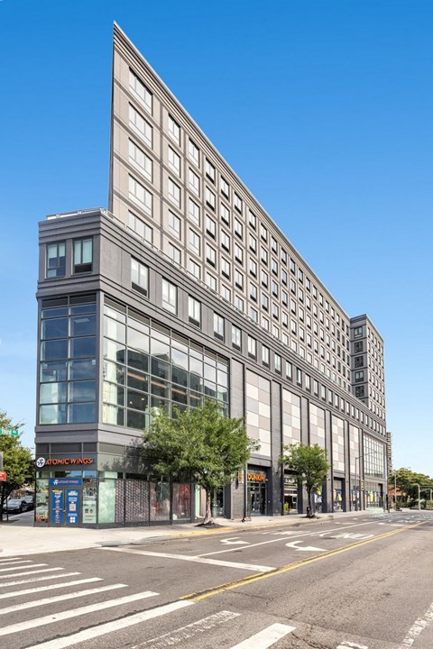 A tall building with a glass facade stands on a street corner.