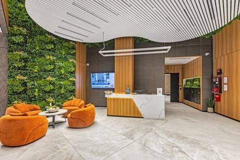 A reception area with orange chairs and a green wall.