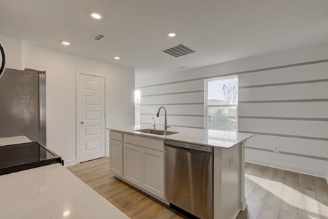 A modern kitchen with a stainless steel dishwasher and white countertops.
