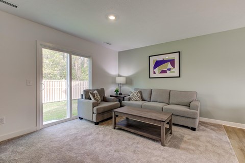 A living room with a grey couch, a coffee table, and a painting on the wall.
