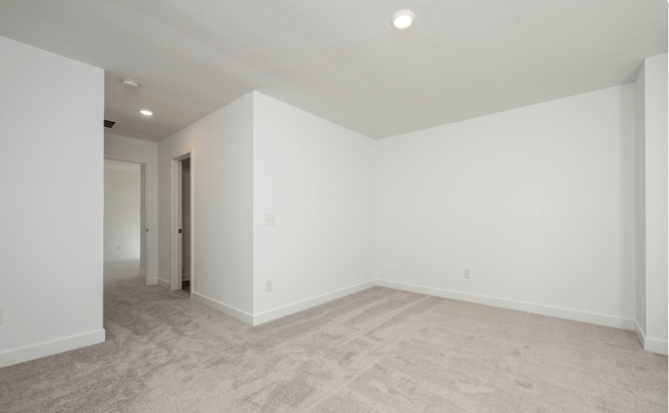 A spacious room with carpeted floor and white walls.
