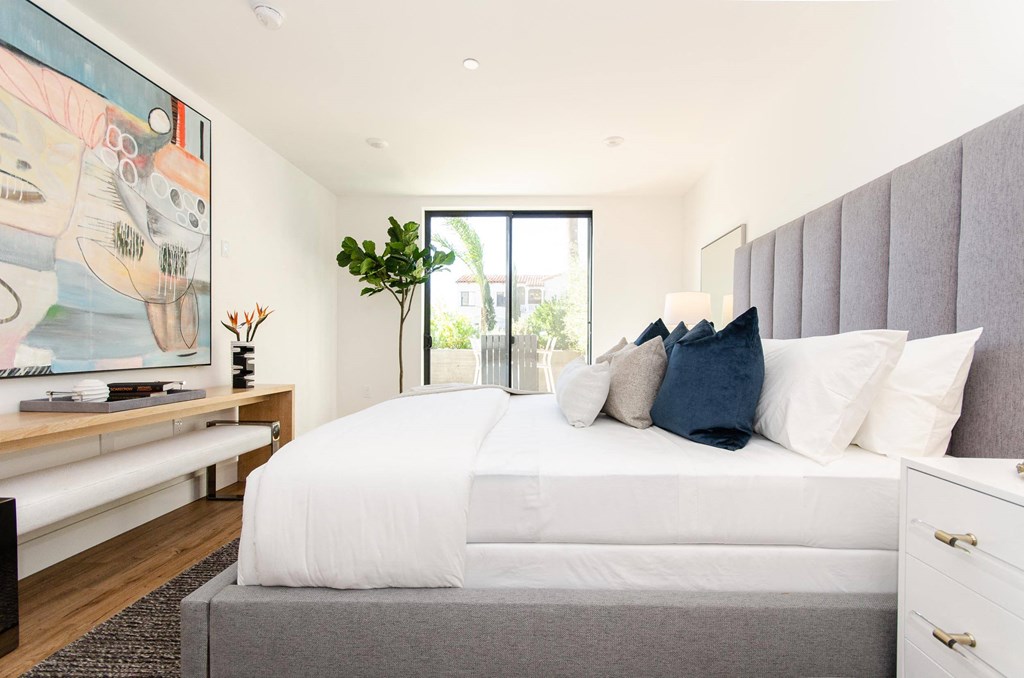 A bedroom with a large bed and a painting on the wall.