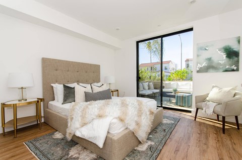 A bedroom with a large bed and a chair.