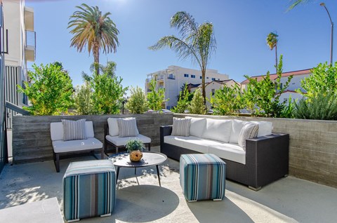 A patio with a white couch, two chairs, and a coffee table.