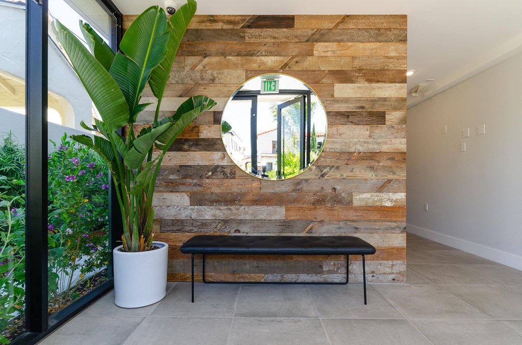 A round mirror hangs on a wooden wall above a bench.