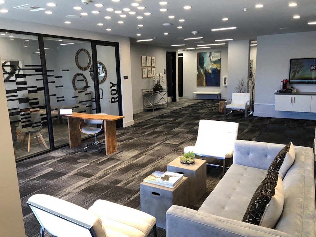 A modern community room with a grey couch and a wooden coffee table.