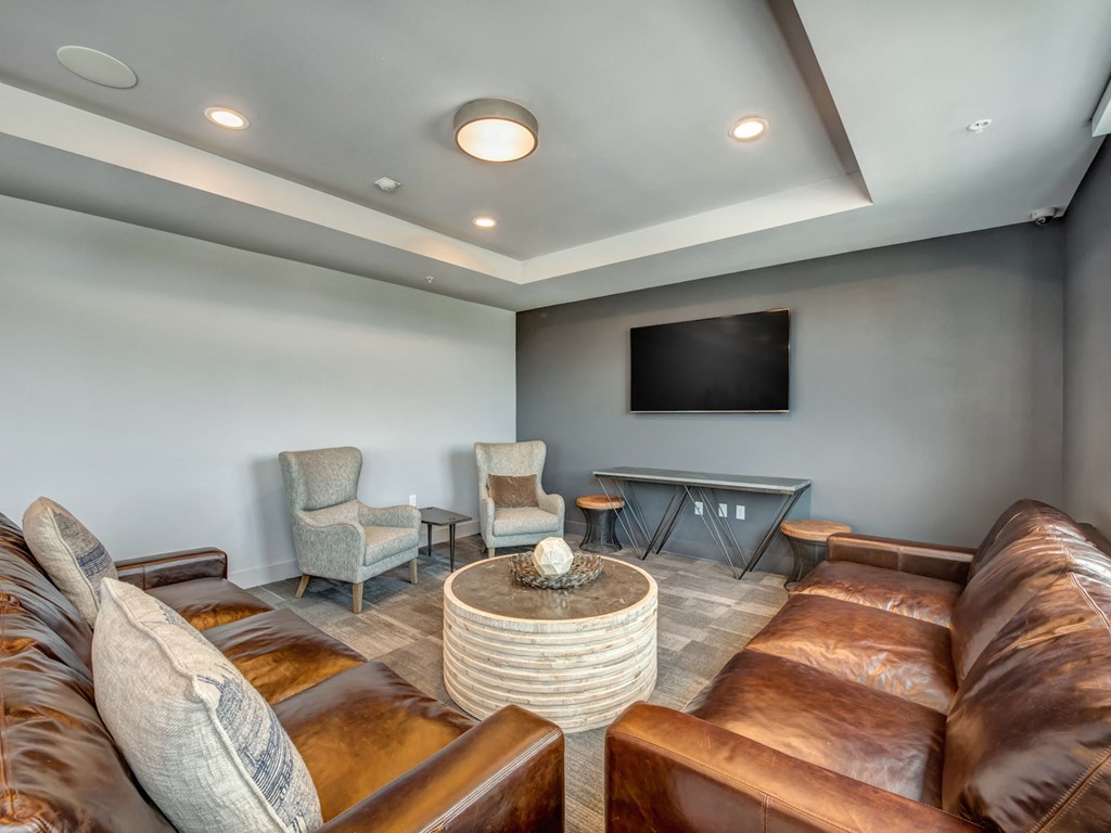 A living room with brown leather couches and a flat screen TV mounted on the wall.