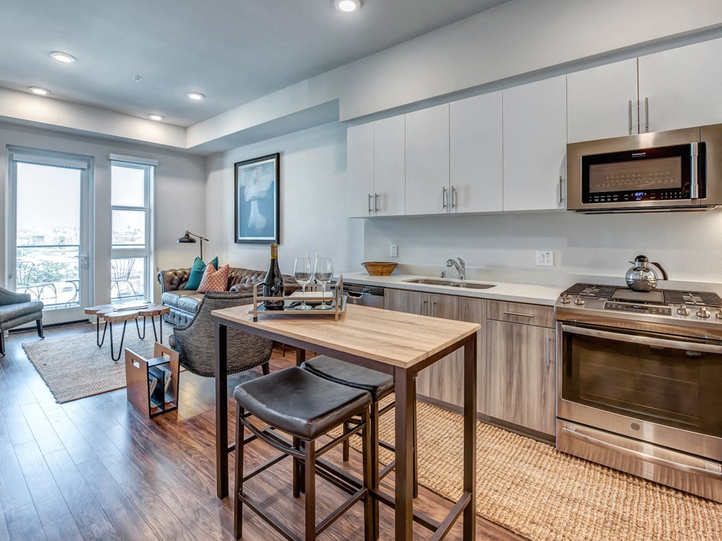 A modern kitchen with a wooden table and bar stools.