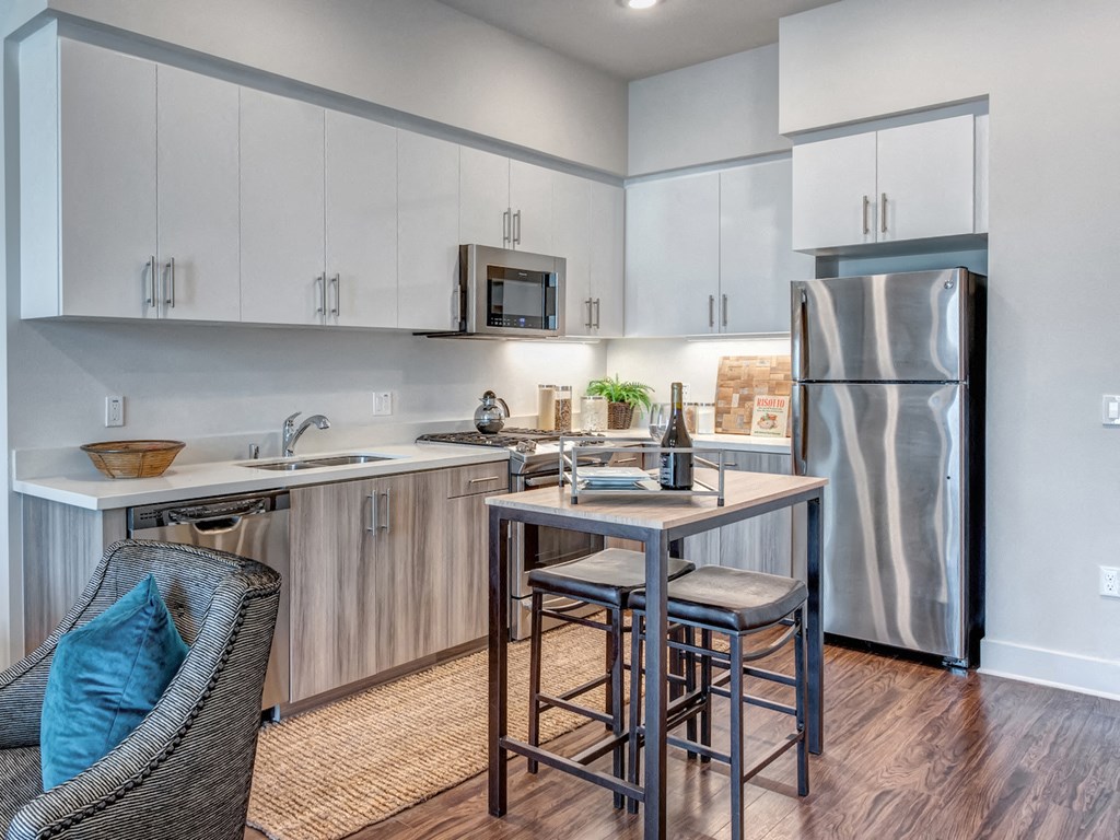A kitchen with a refrigerator, sink, and bar stools.