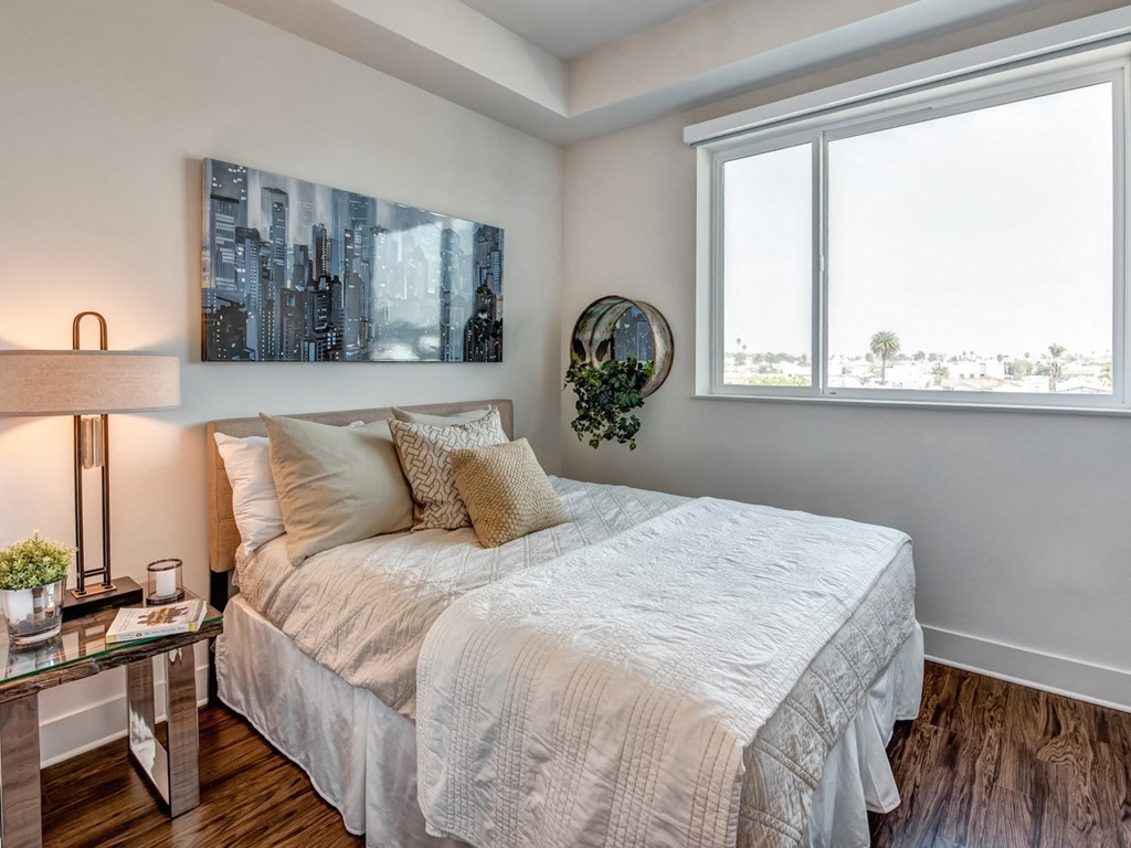 A bedroom with a large bed and a cityscape painting on the wall.