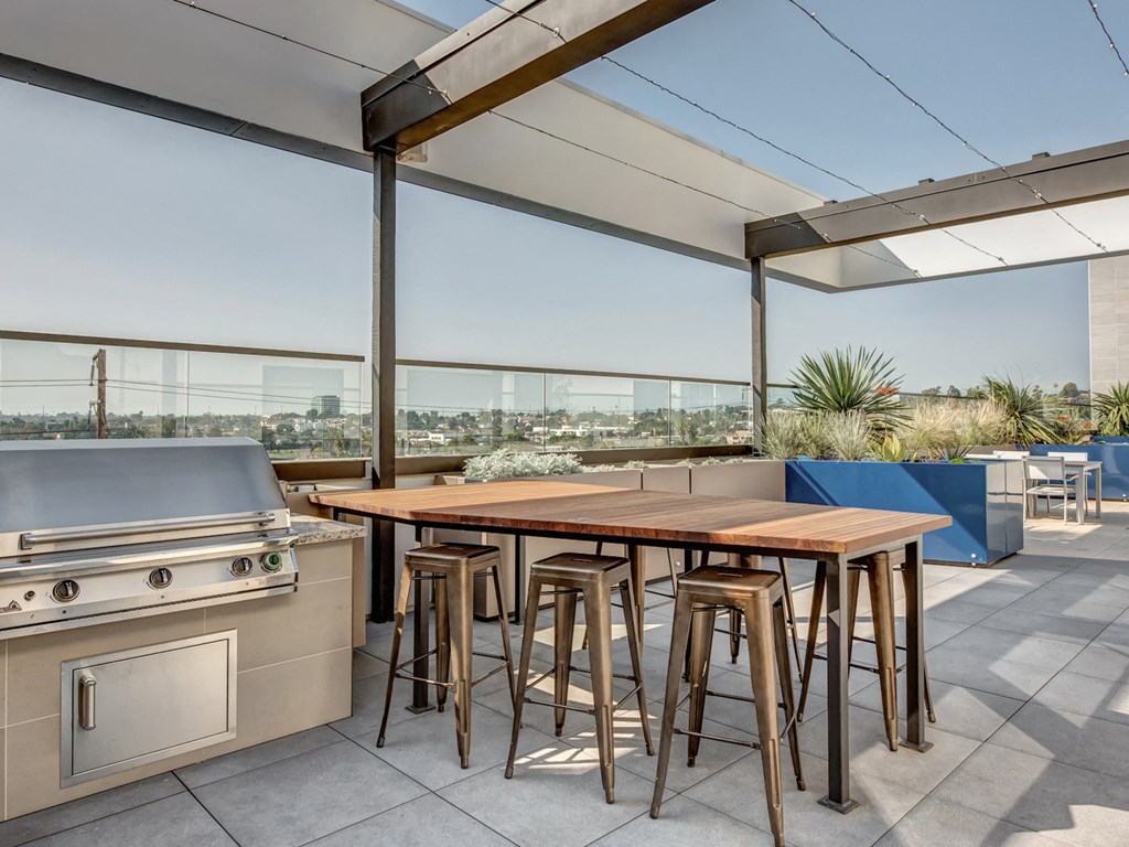 A modern outdoor kitchen with a grill and bar stools.