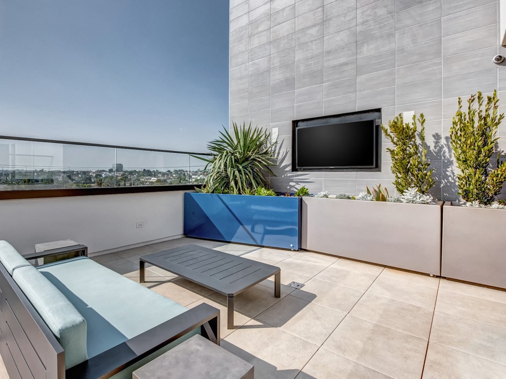 A modern balcony with a blue cushion and a flat screen TV.