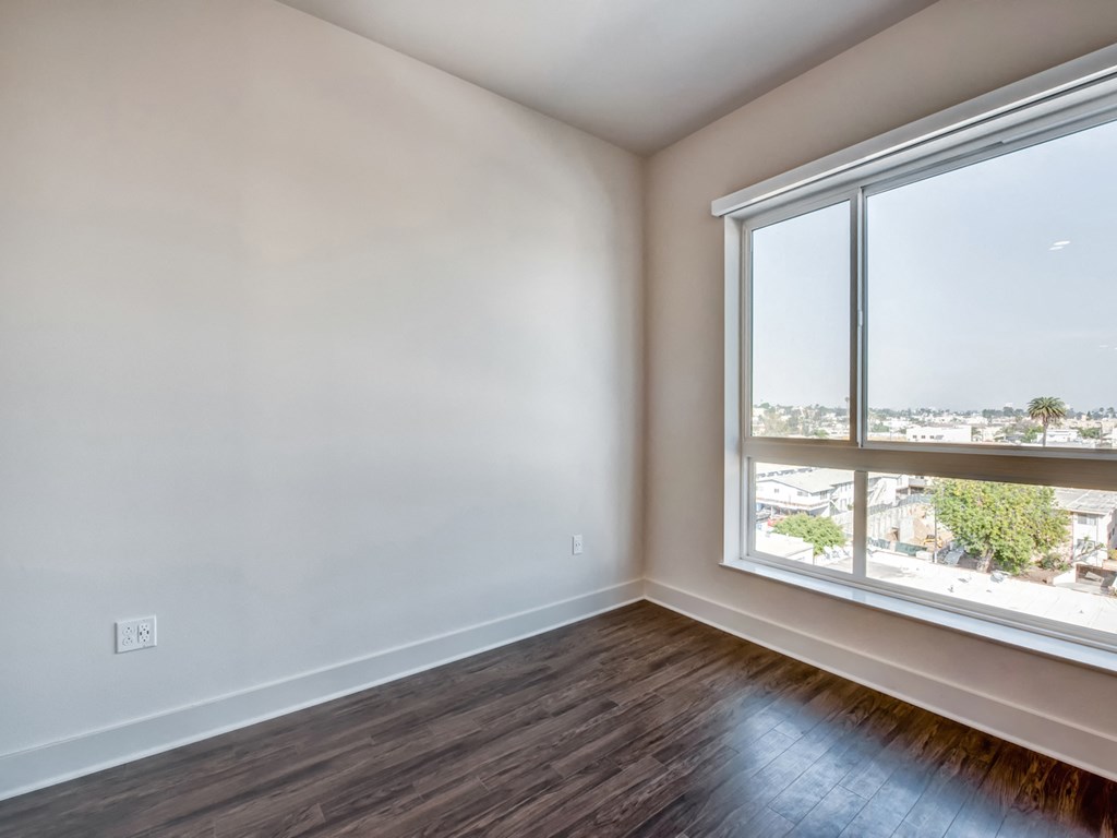 A room with a large window and wooden flooring.