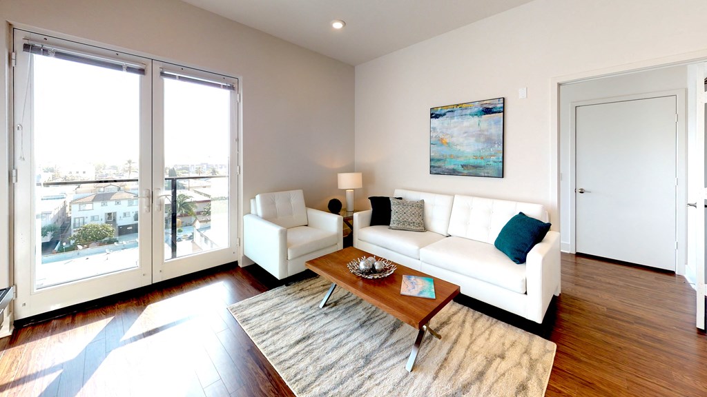 A living room with a white couch and a painting on the wall.