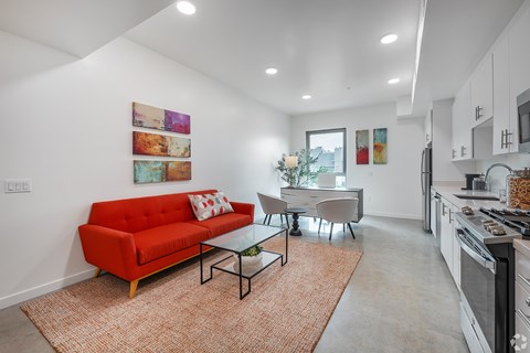 A red couch sits in a living room with a glass table and chairs.