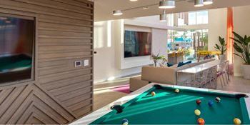 A billiard table is in the middle of a room with a television and a couch.