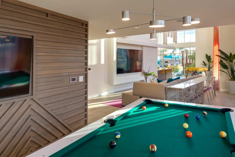 A pool table in a room with a wooden wall and a TV.