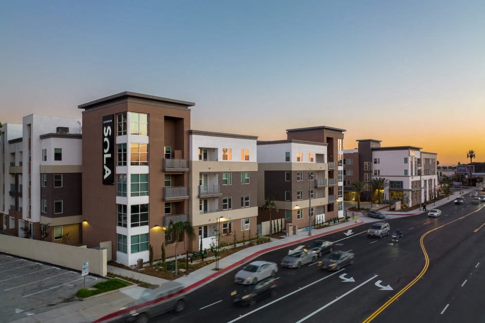 A sunset view of a street with cars and buildings.