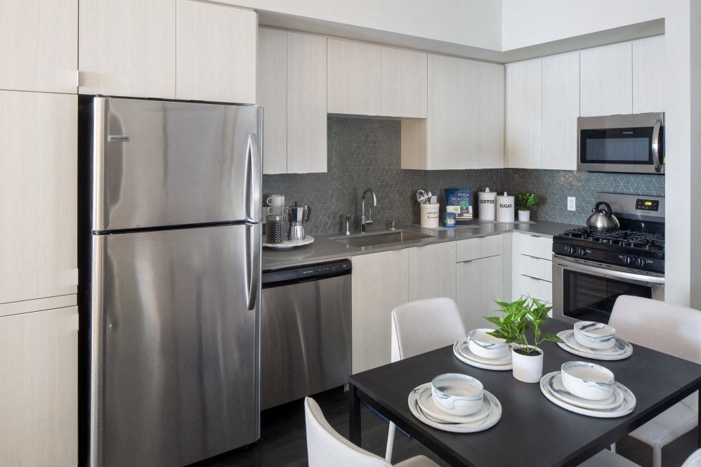 A modern kitchen with a stainless steel refrigerator and a dining table set for two.