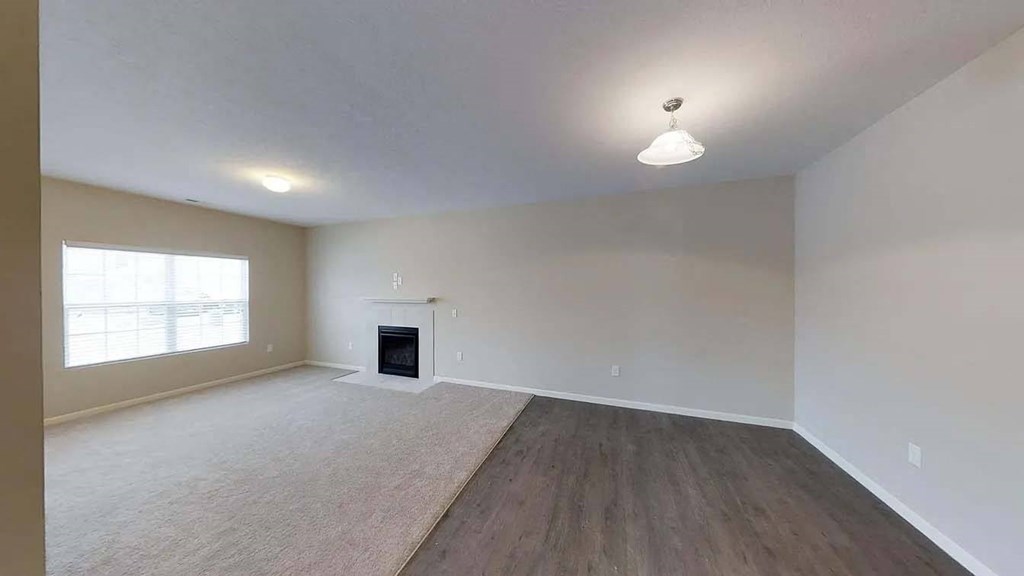 an empty living room with a fireplace and a window