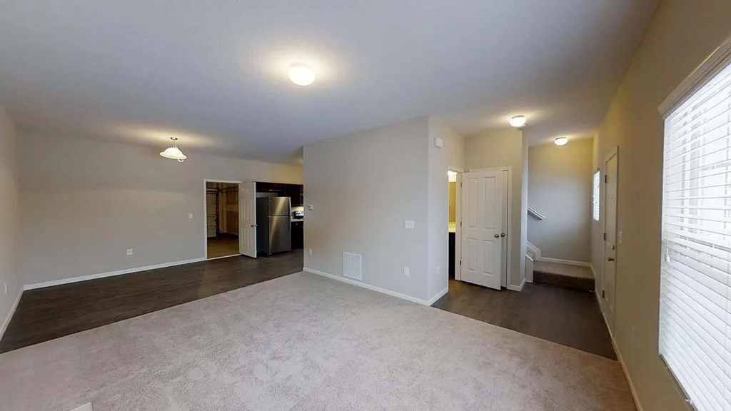 an empty living room and kitchen with a large window