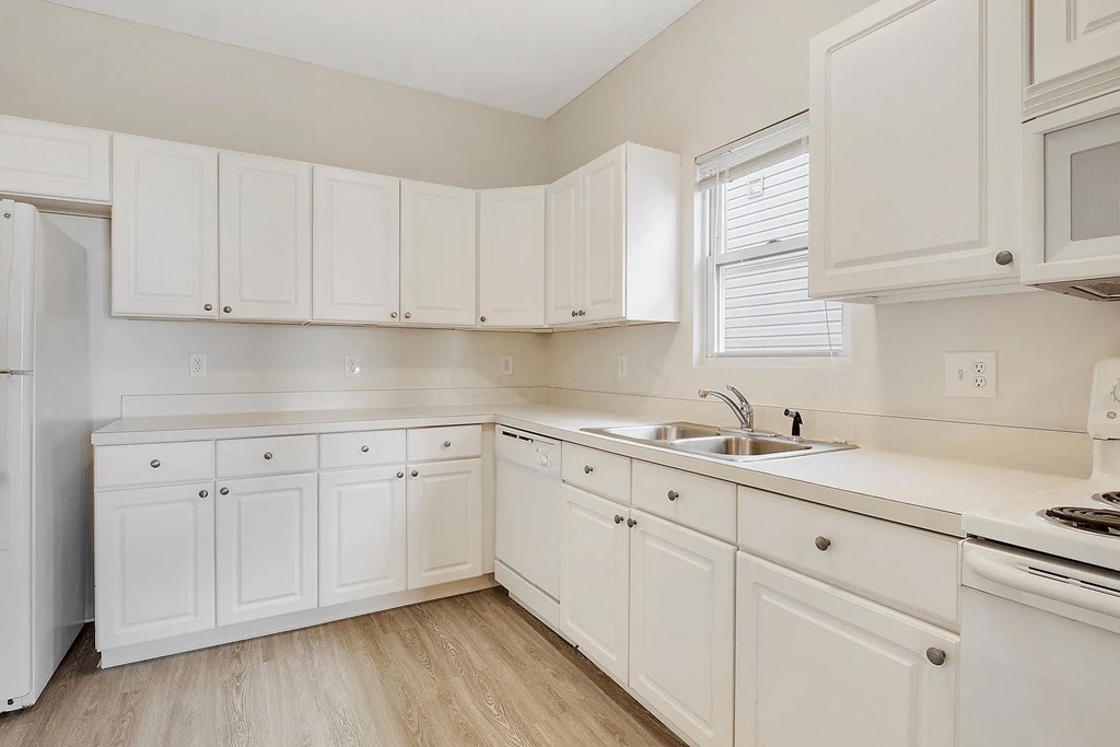 A kitchen with white cabinets and appliances.