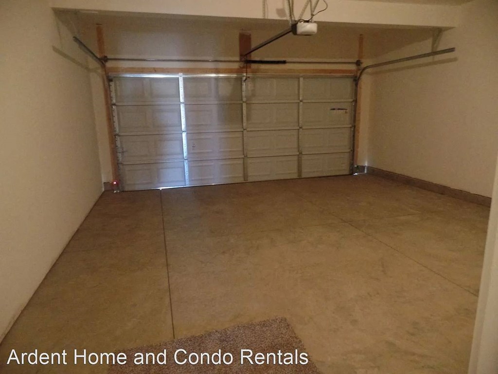A spacious garage with a closed white door and a brown floor.