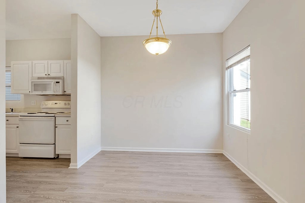 an empty living room with white walls and a kitchen