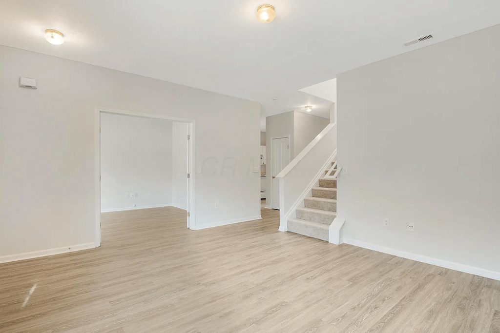A spacious room with a staircase leading to another floor.