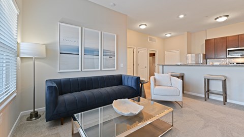 A living room with a blue couch and a glass coffee table.