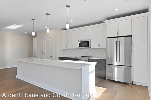 A modern kitchen with white cabinets and stainless steel appliances.