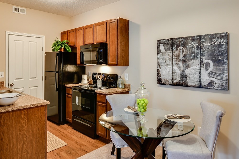 A kitchen with a glass table and a fridge.