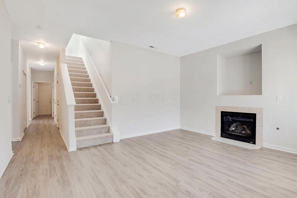 a renovated living room with a staircase and a fireplace