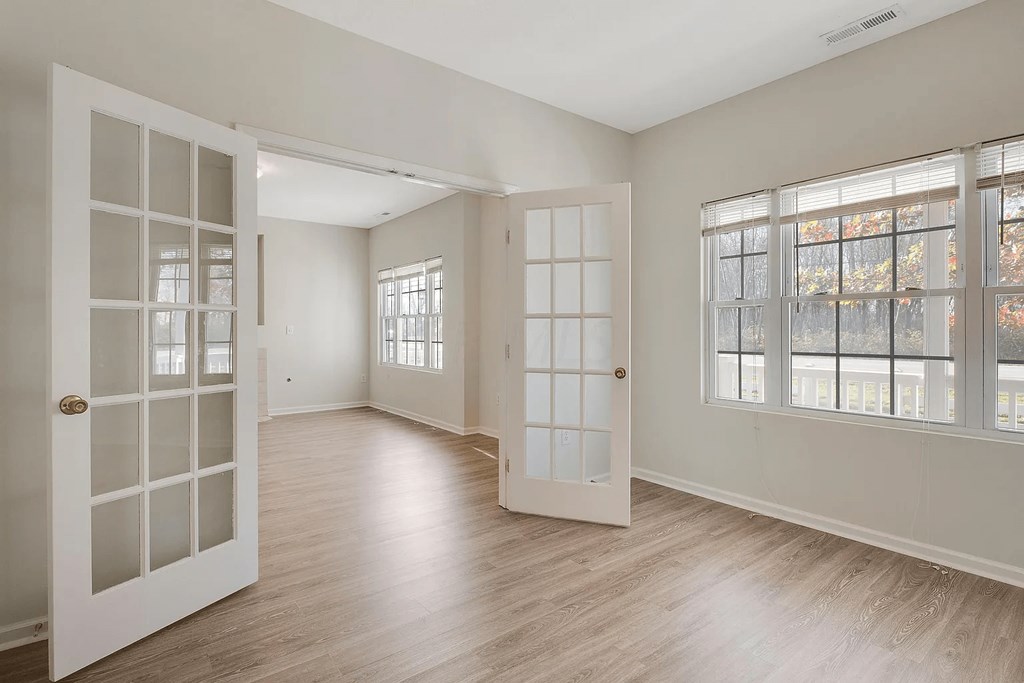 the living room and dining room of an empty home doors