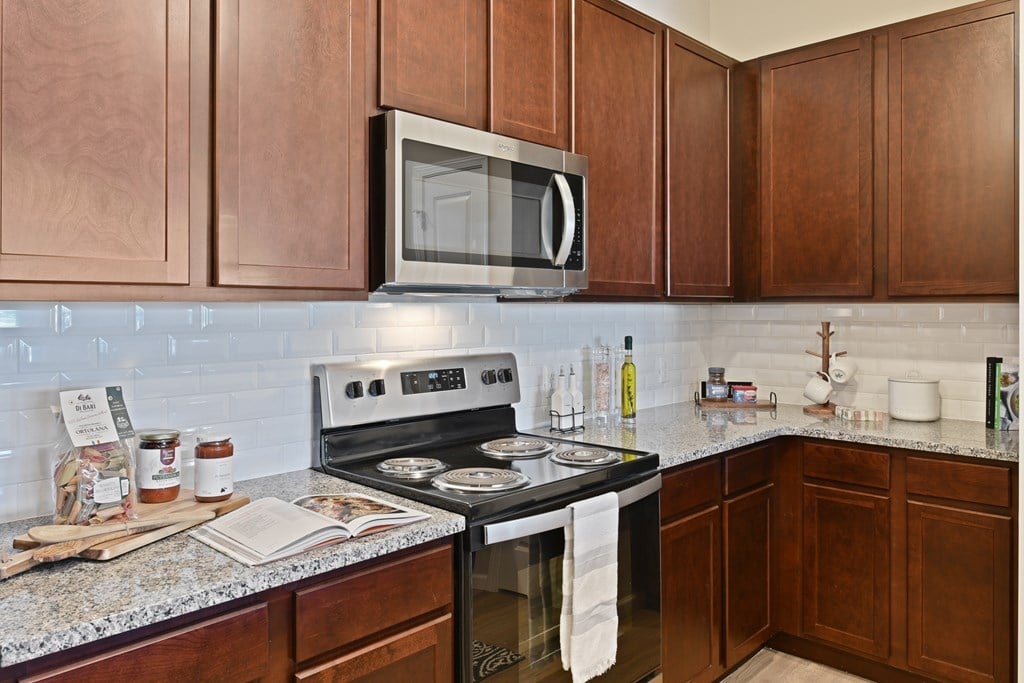 A kitchen with a black stove top oven and a microwave above it.