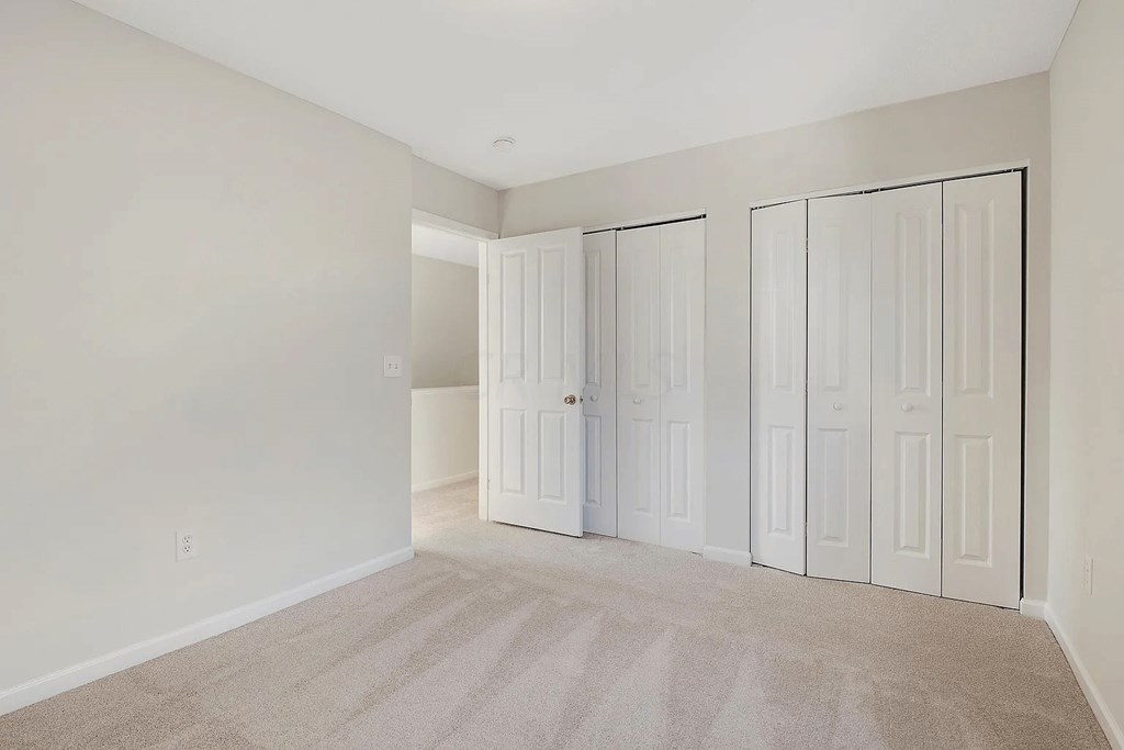 a bedroom with two closets and a carpeted floor