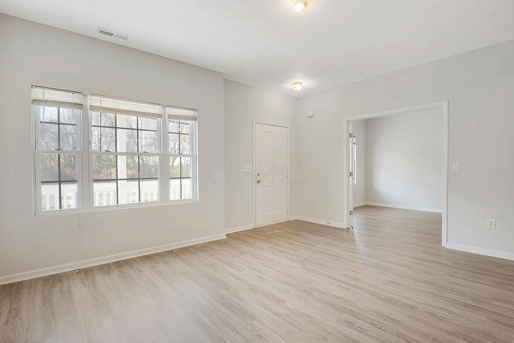 A room with a window and a door is empty and waiting to be furnished.