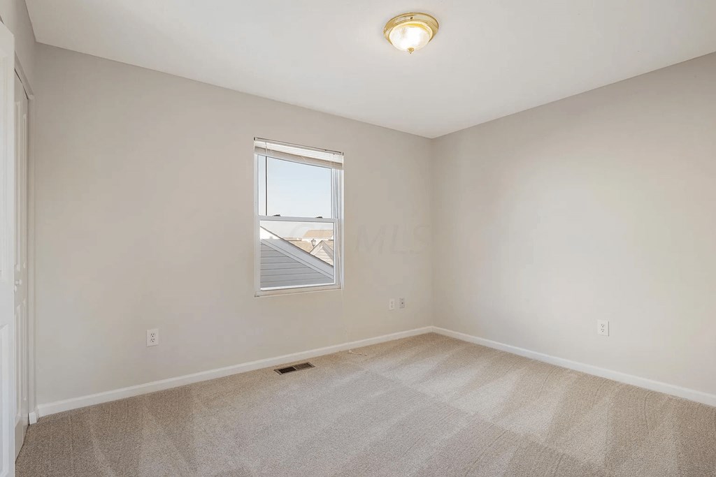 A room with a carpeted floor and a window.