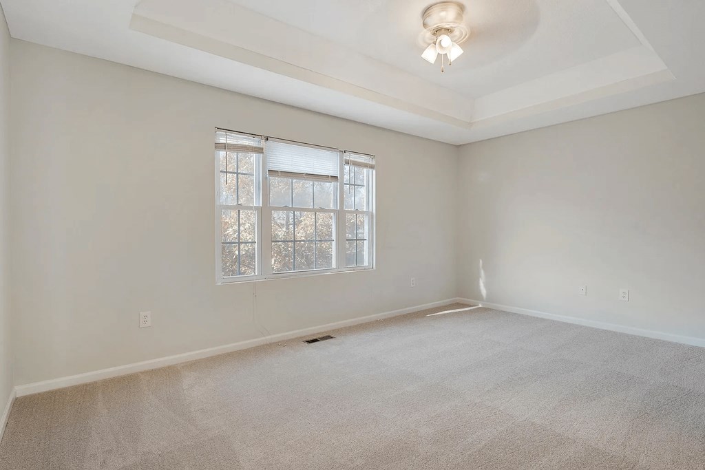 an empty living room with a window and carpet